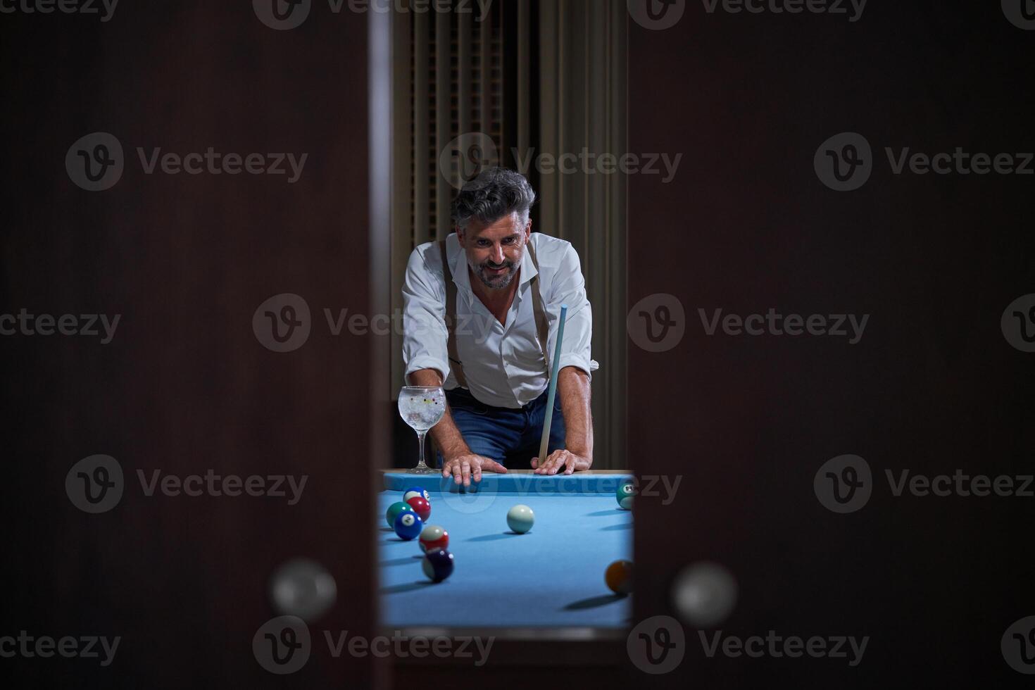 Male with cue playing billiards at home photo