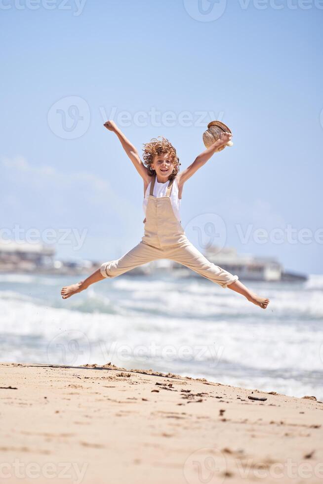 Carefree boy jumping on sandy beach photo