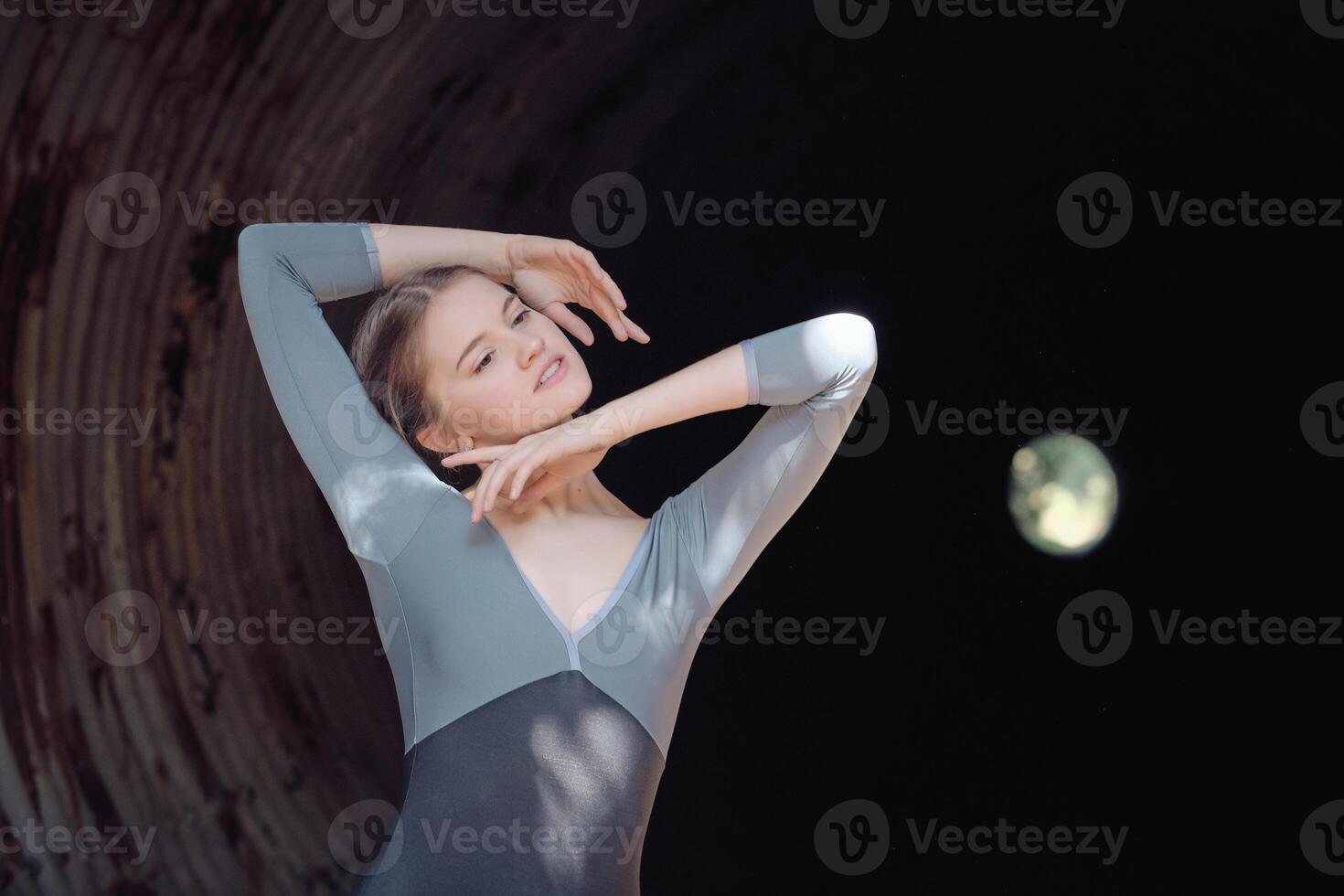 Graceful woman dancing in dark tunnel photo