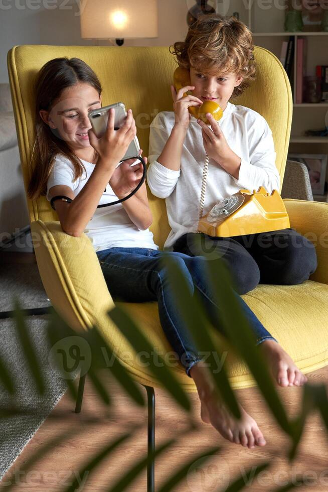 Content children using old telephone and new smartphone photo