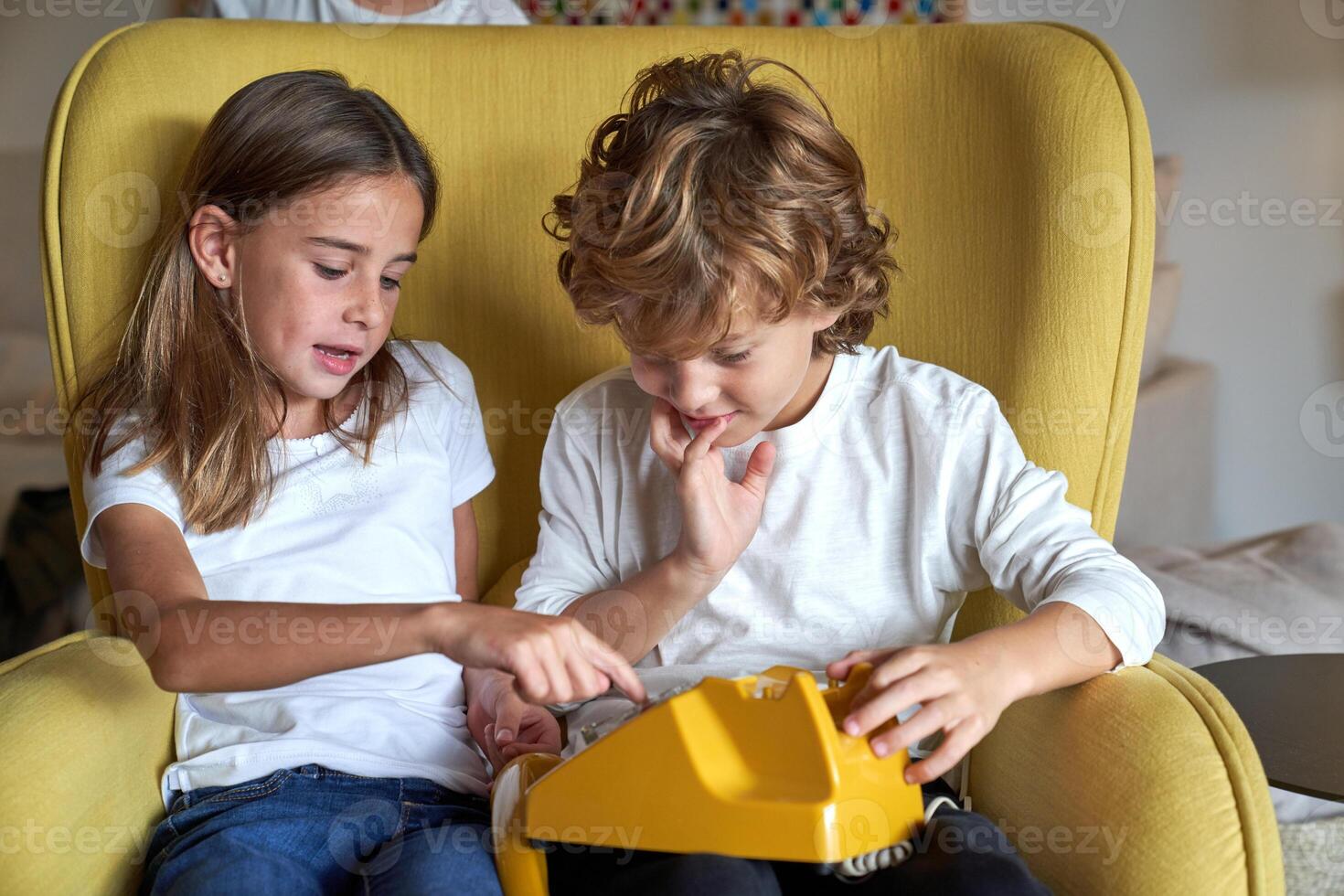 Siblings dialing number on old fashioned telephone photo