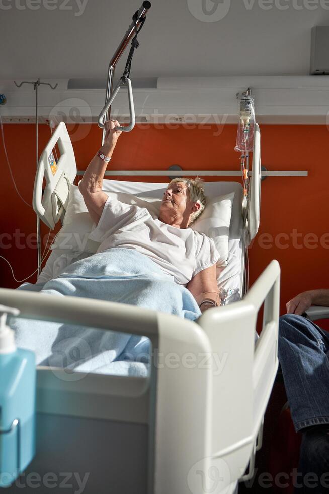 Elderly unwell woman lying on medical bed in hospital photo