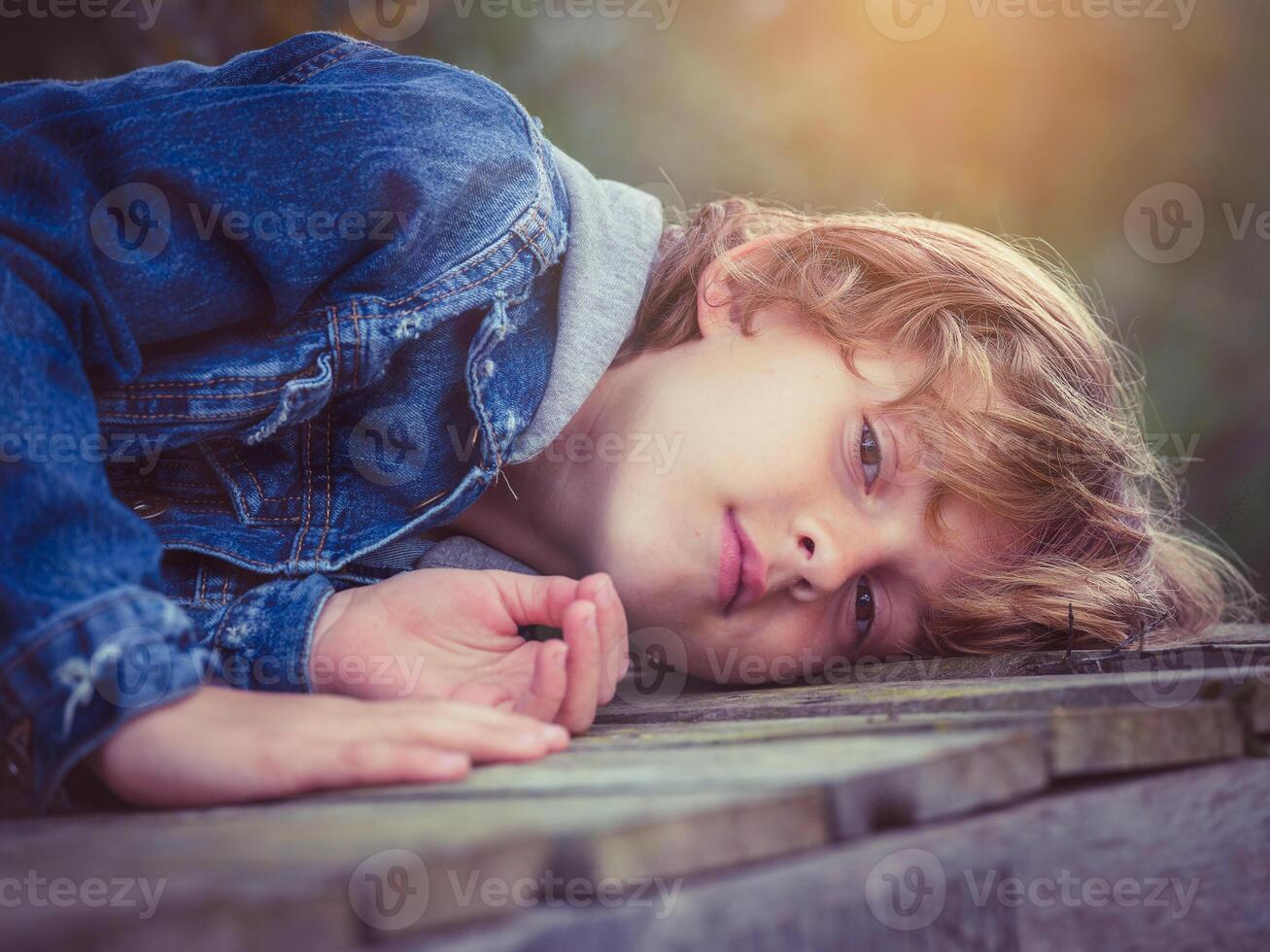 Boy lying on boardwalk and looking at camera photo