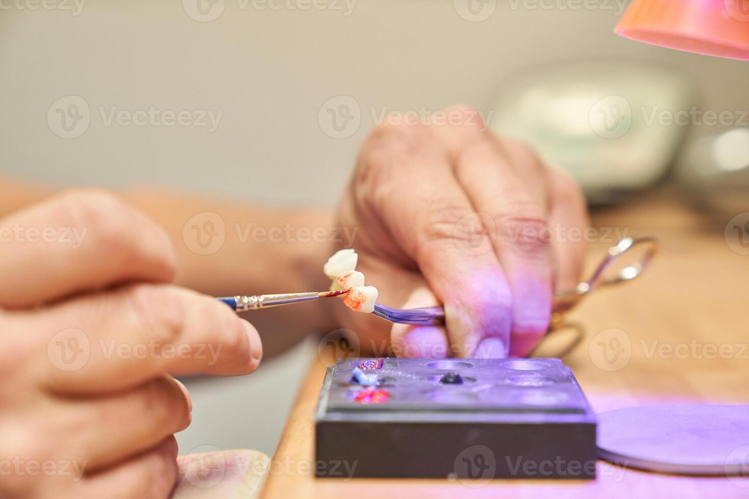 Anonymous dental specialist painting denture photo