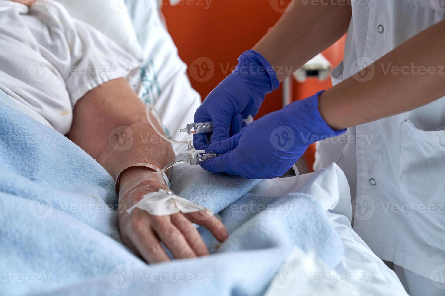 Unrecognizable nurse making injection in catheter of patient photo