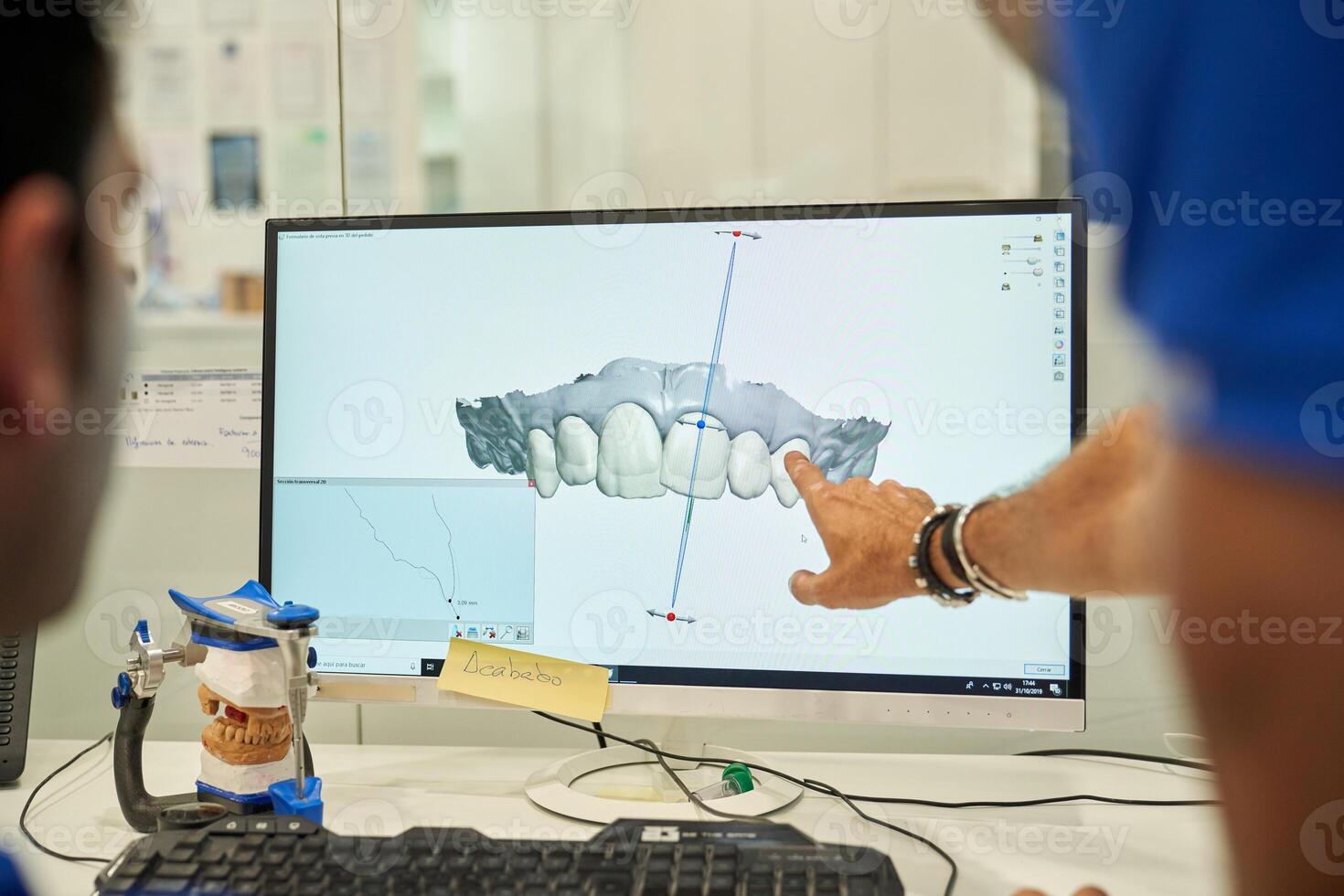 Unrecognizable prosthodontists examining denture on computer photo