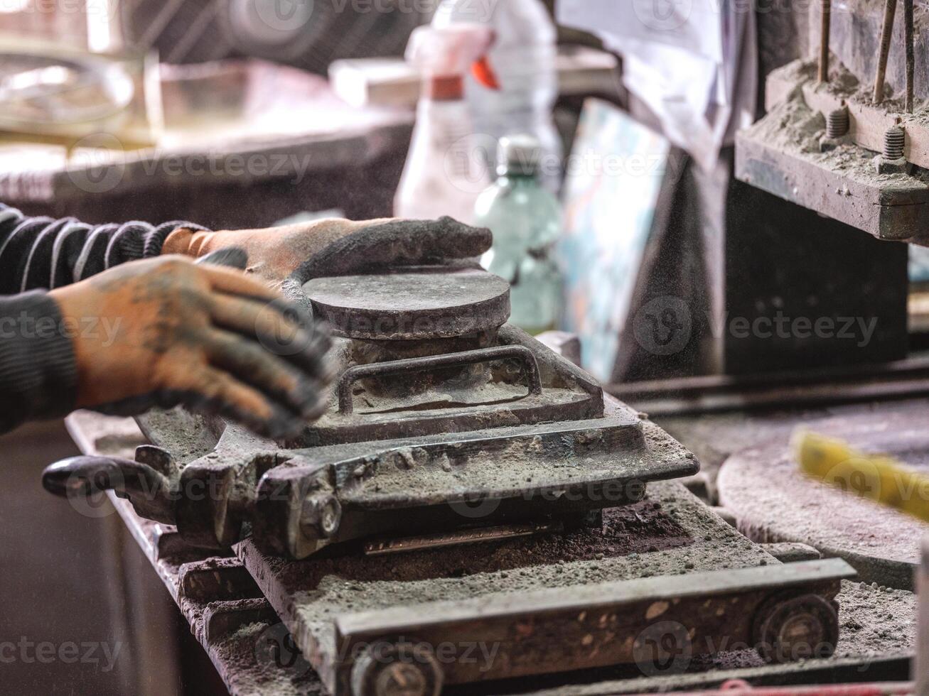Crop craftsman pouring dry clay into mold while creating tile photo