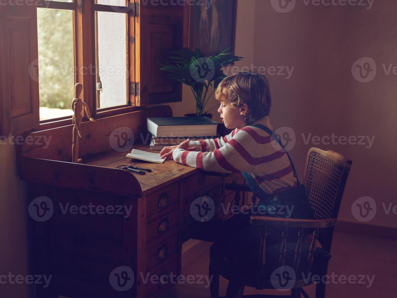 Focused pupil sitting at table and doing homework photo