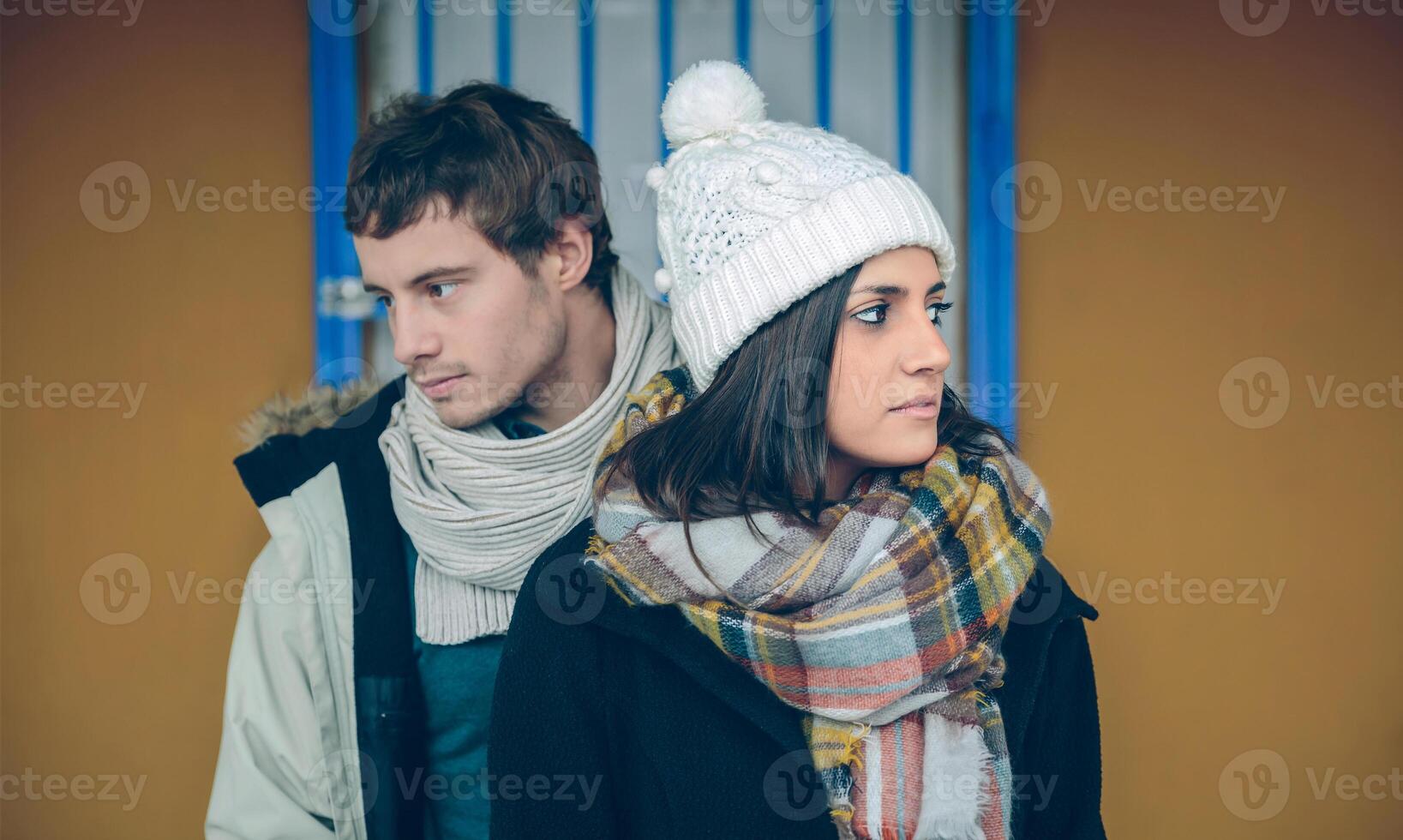 Couple wearing winter clothes standing and looking sideways photo
