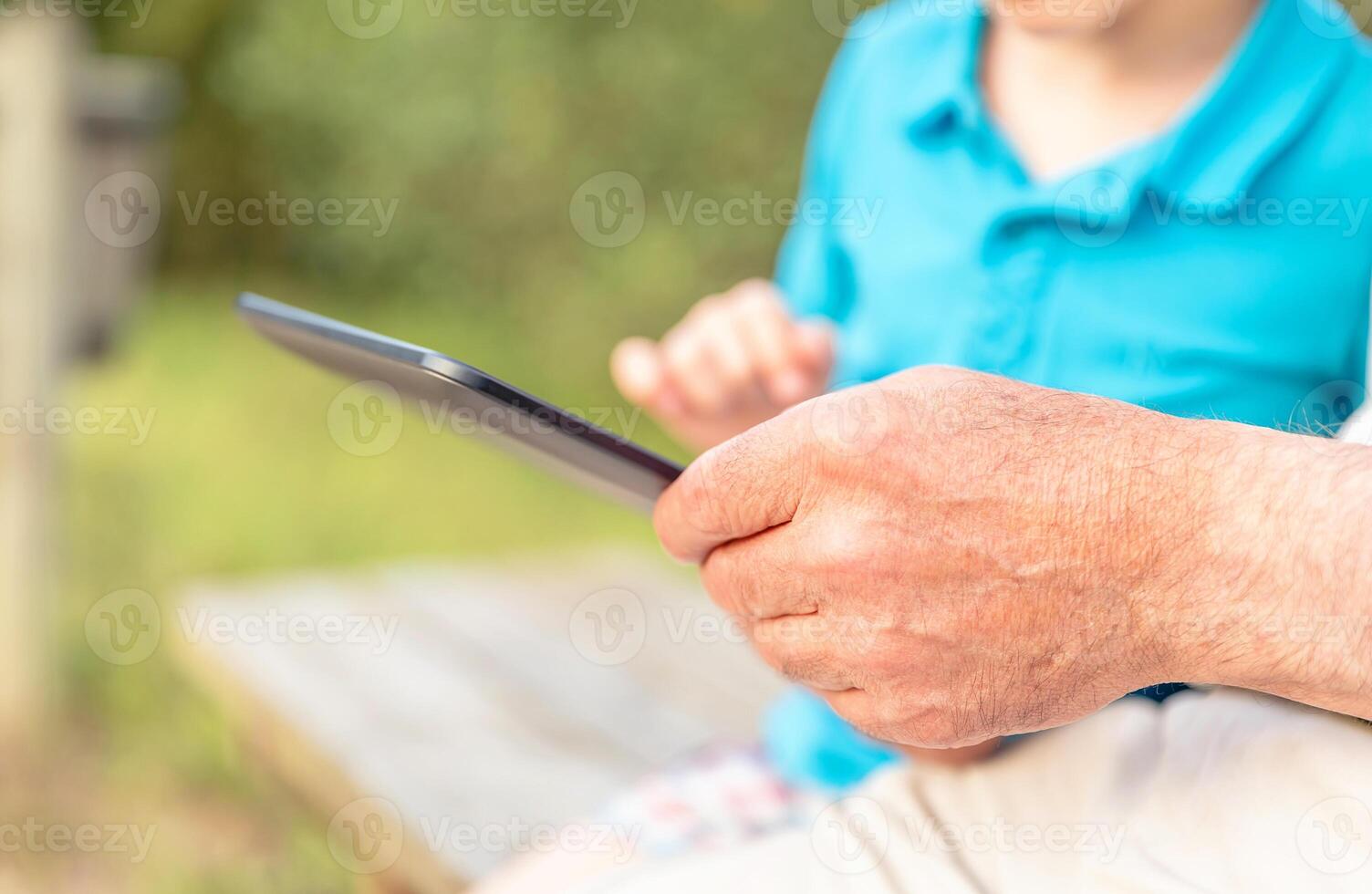 Grandfather hands using tablet with granchild photo