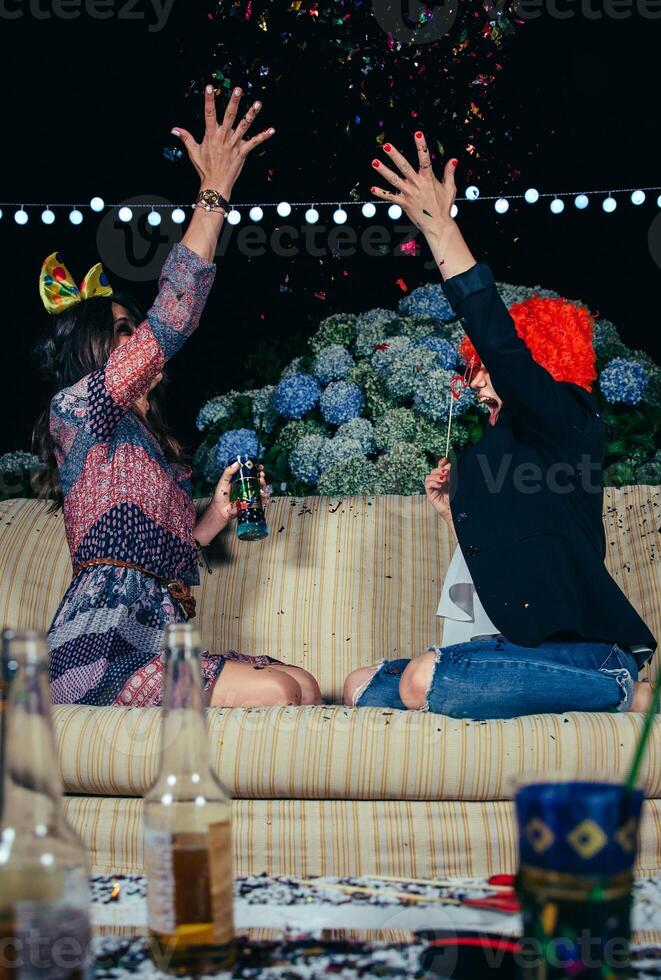 Happy women throwing confetti to the air in party photo
