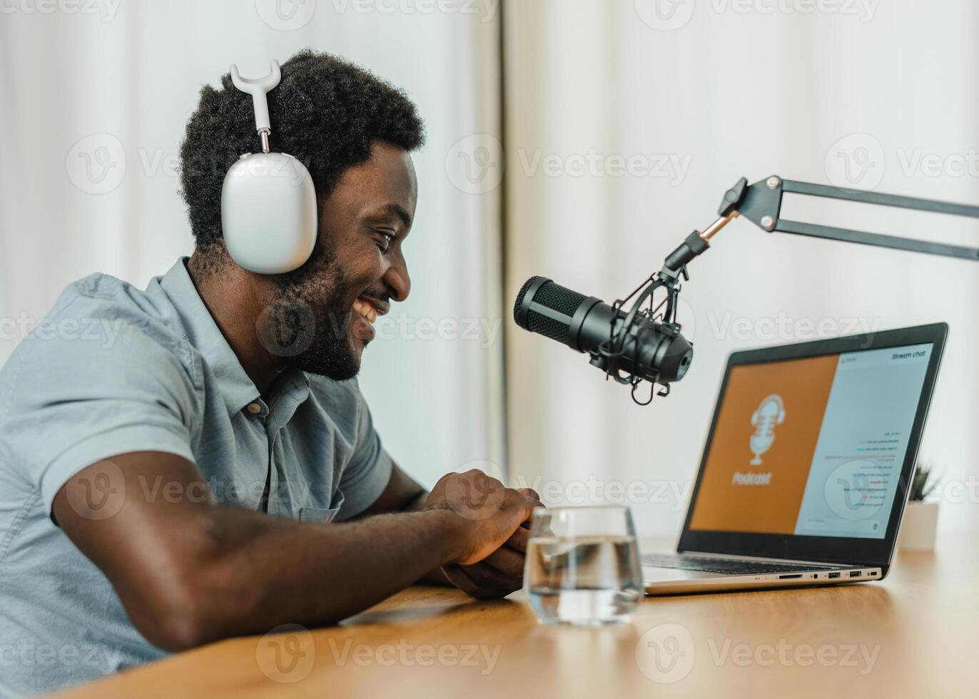 Smiling black man using laptop and recording podcast photo
