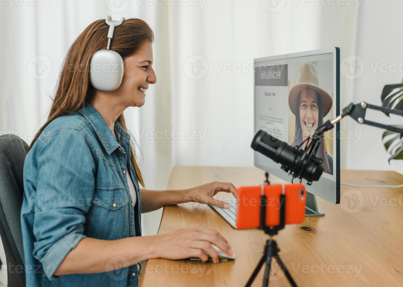 Cheerful woman browsing computer and recording podcast photo