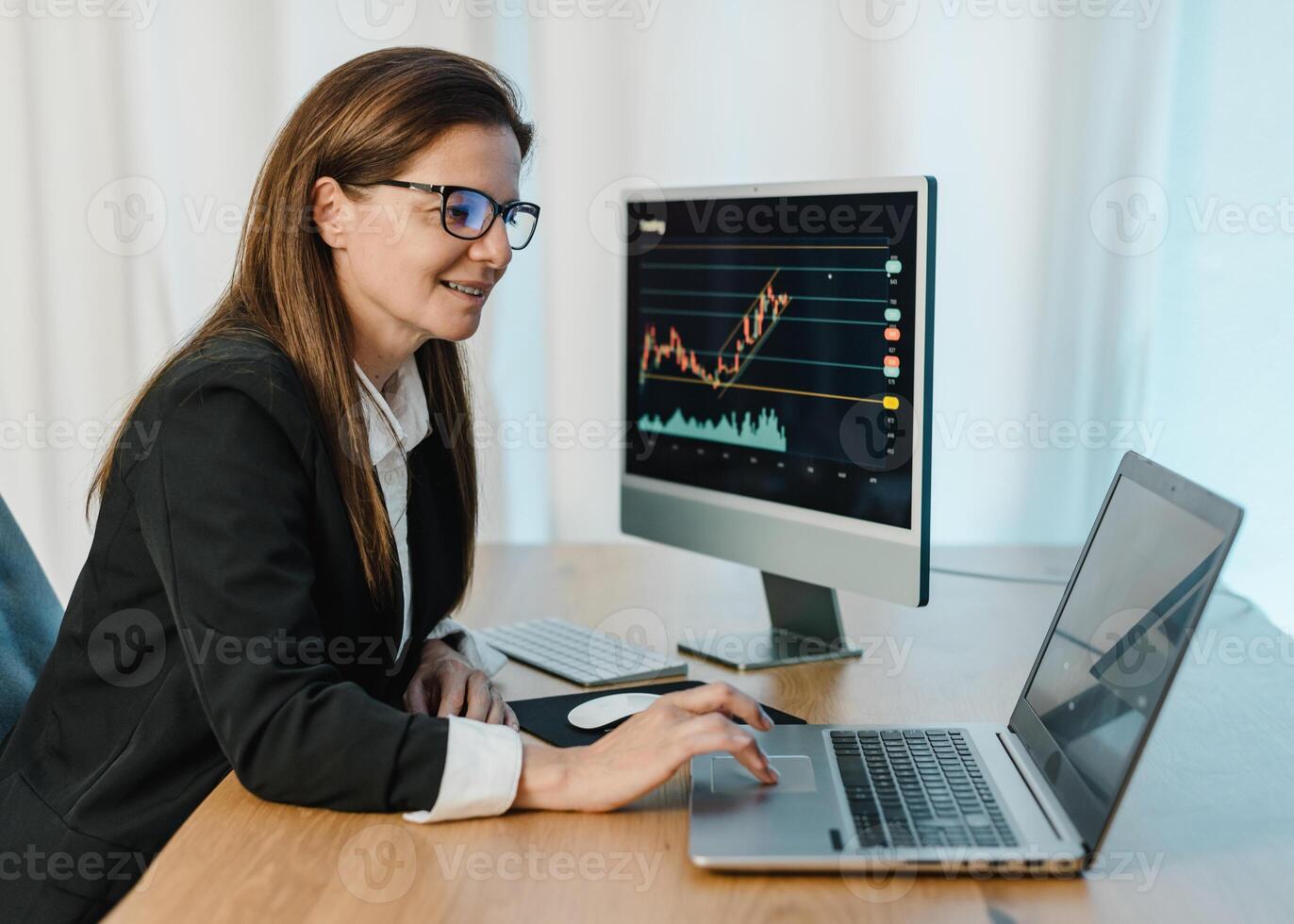 Smiling female trader working on laptop photo