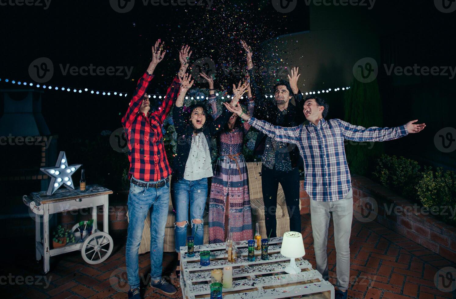 Happy friends having fun among the party confetti photo