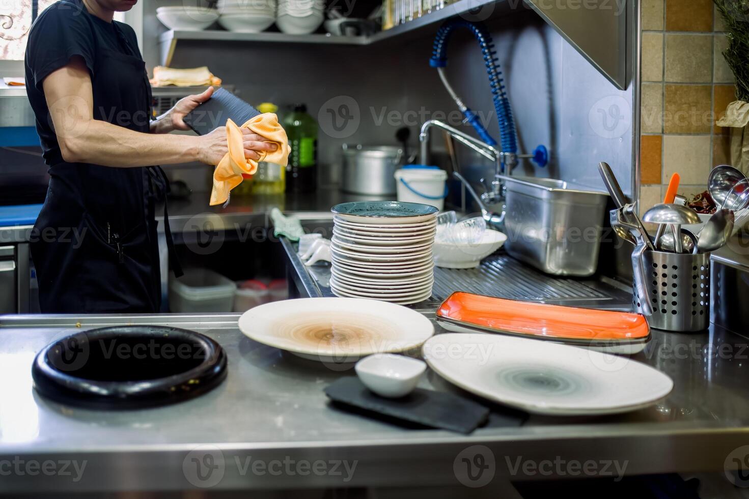 Crop woman cleaning plates in kitchen photo