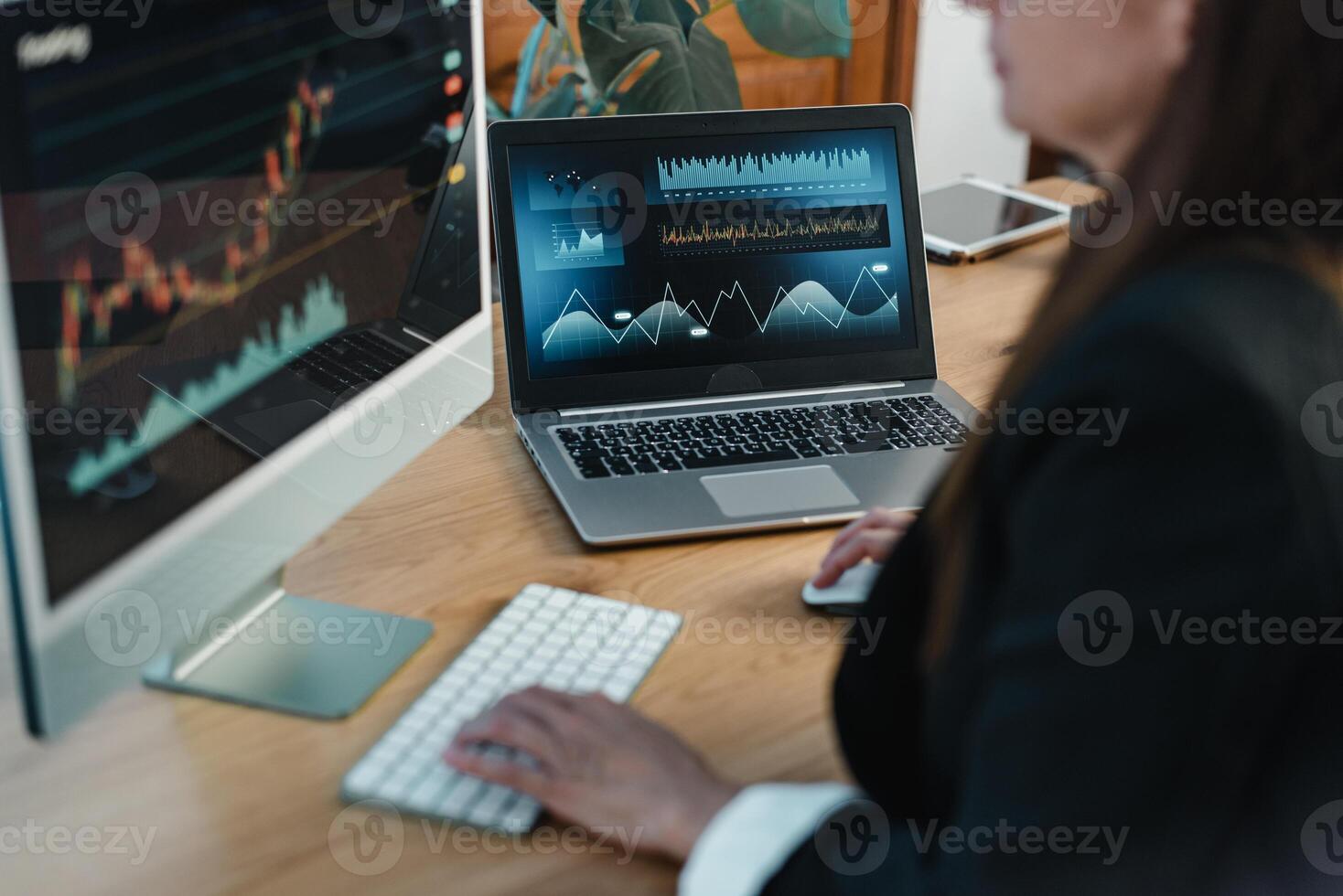 Crop trader at table with laptop and computer screen photo