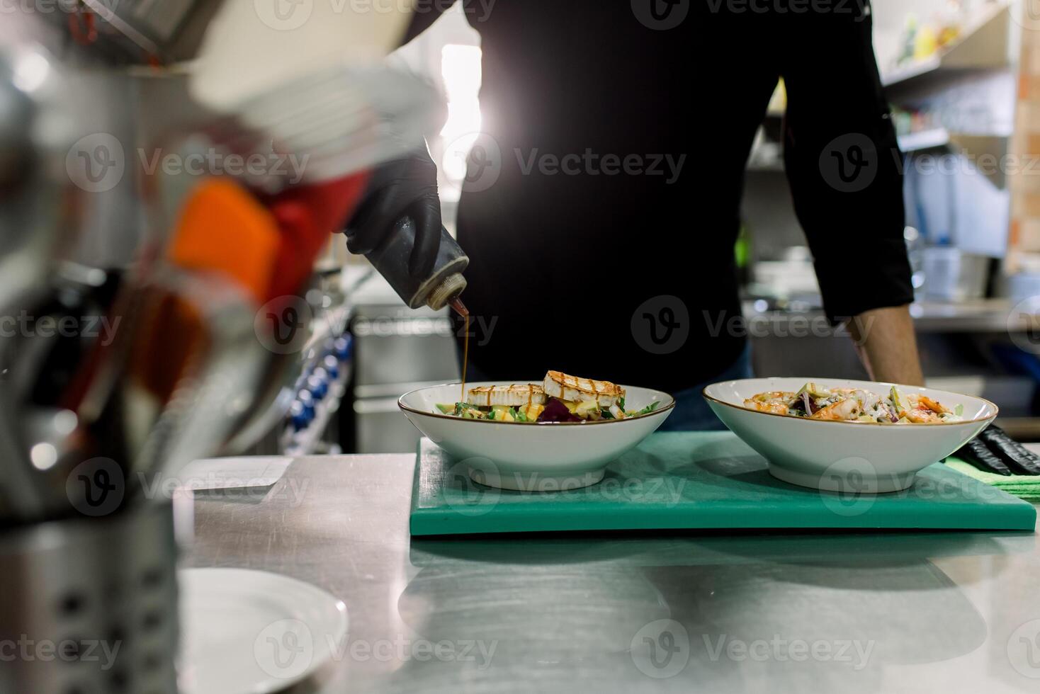 Crop anonymous male chef in black uniform serving delicious salad with grilled cheese in kitchen of restaurant photo