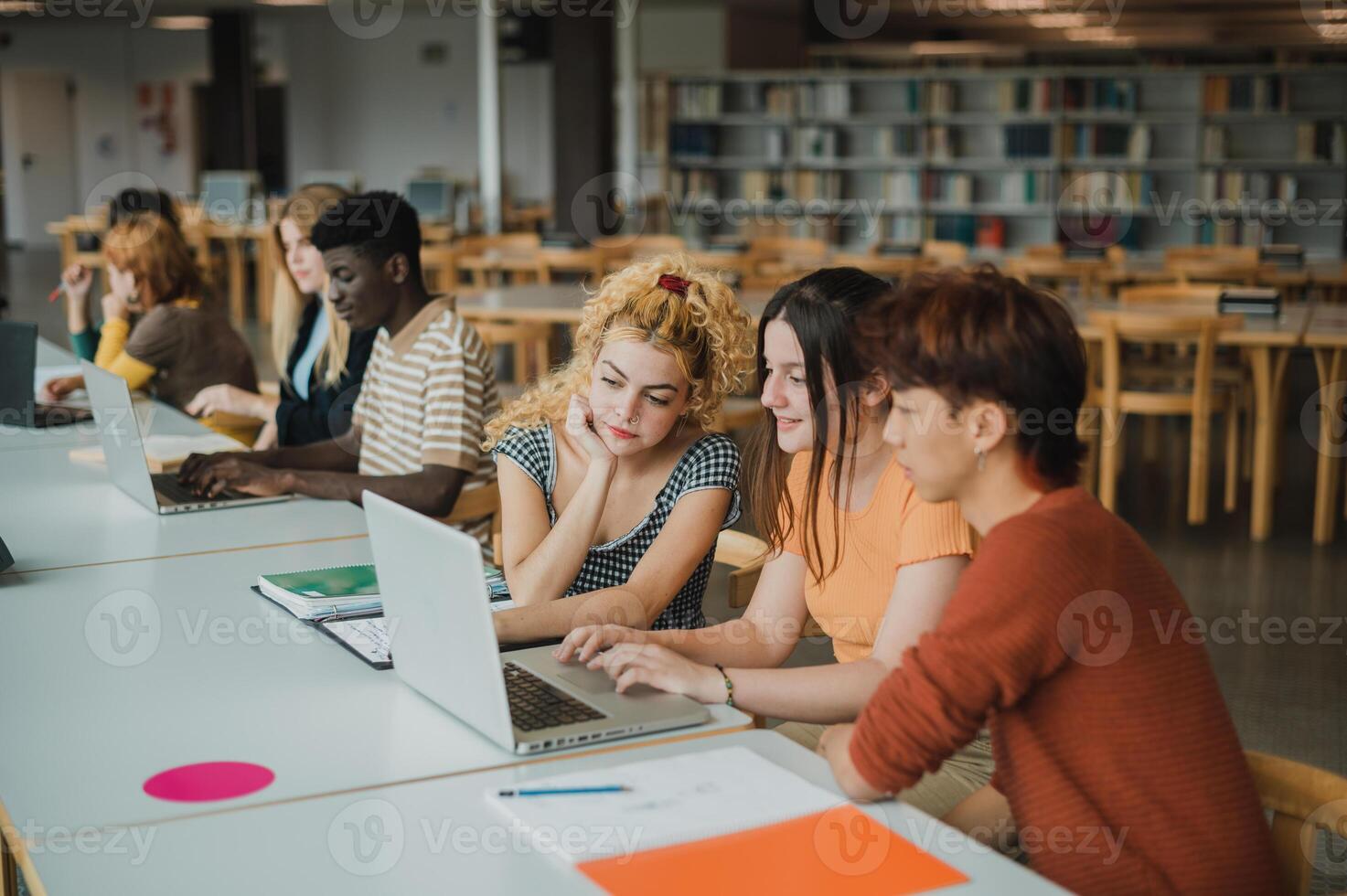 Multiracial young students using netbooks in library photo