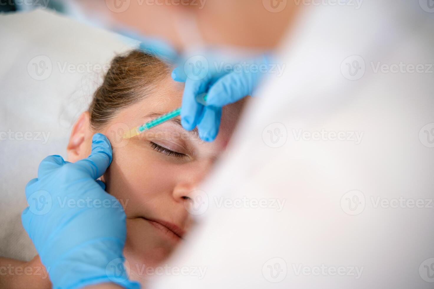 Physiotherapist giving facial injection to client in clinic photo