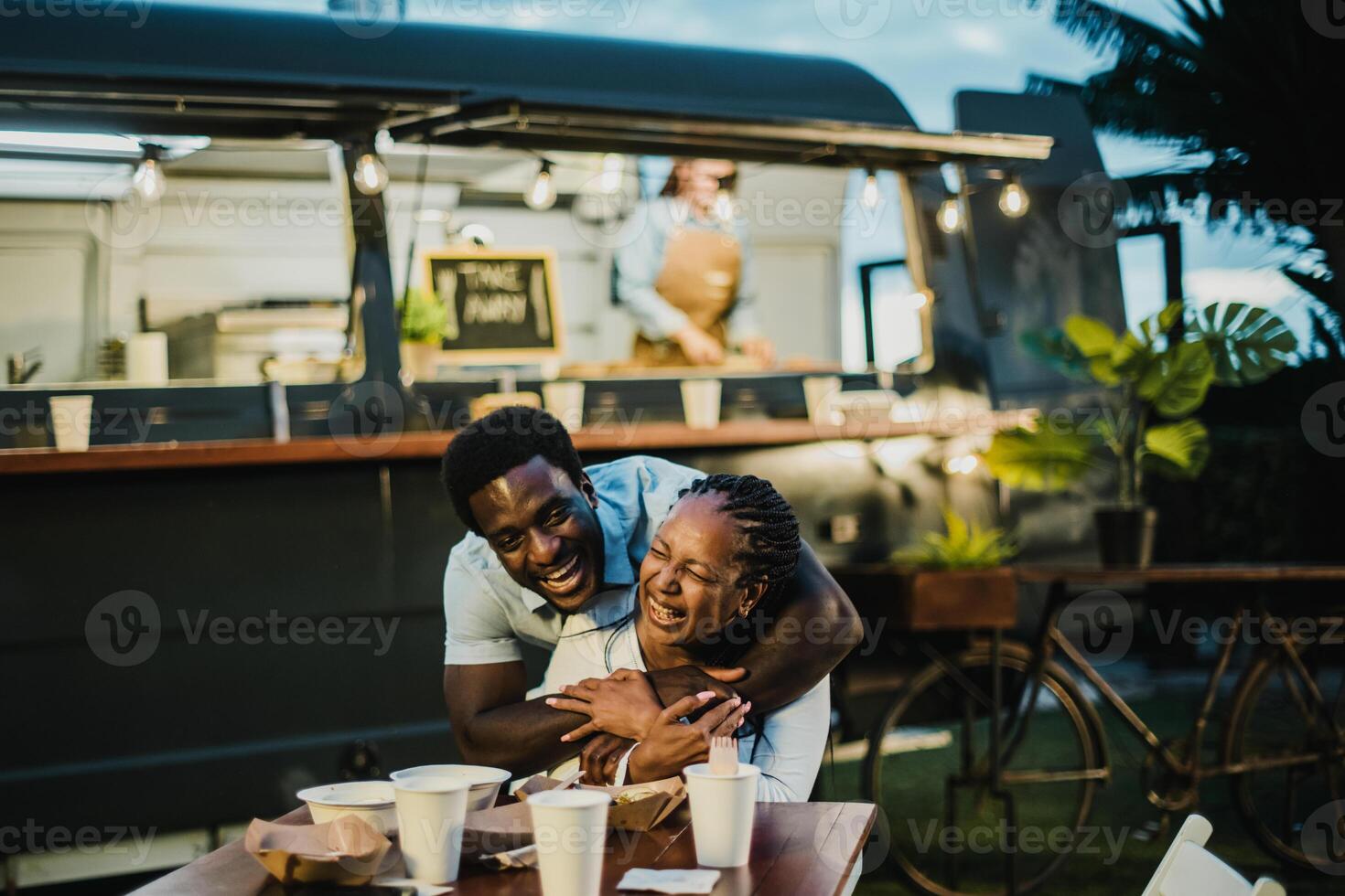 Happy black couple hugging near food truck photo