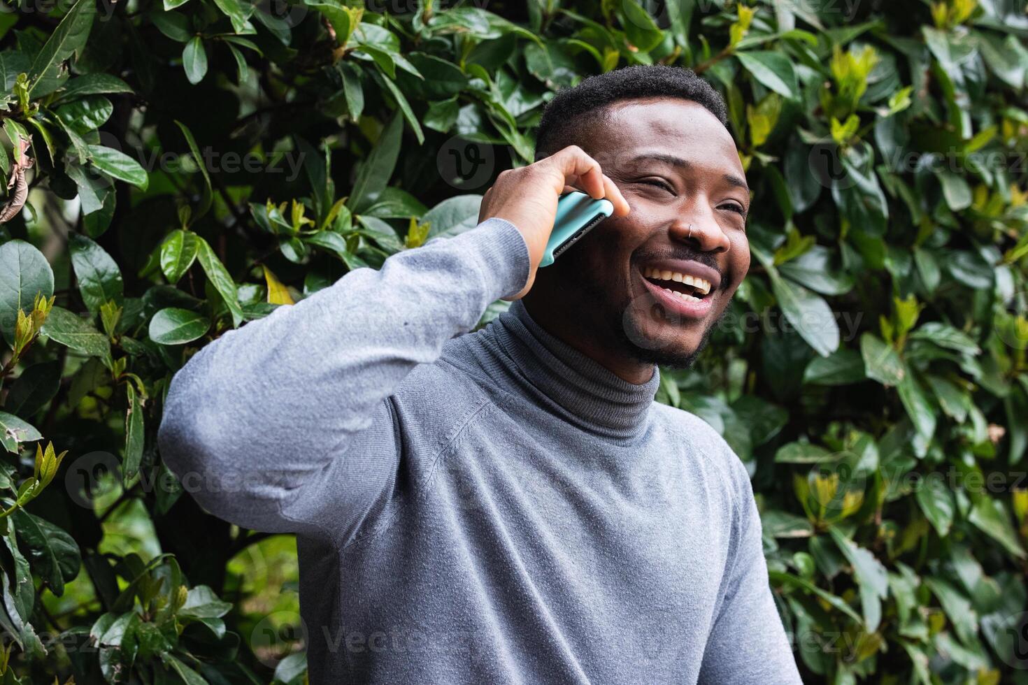 Cheerful black man talking on smartphone in park photo