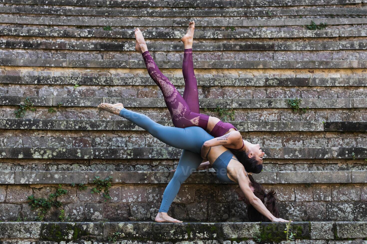 Flexible women practicing acro yoga together photo