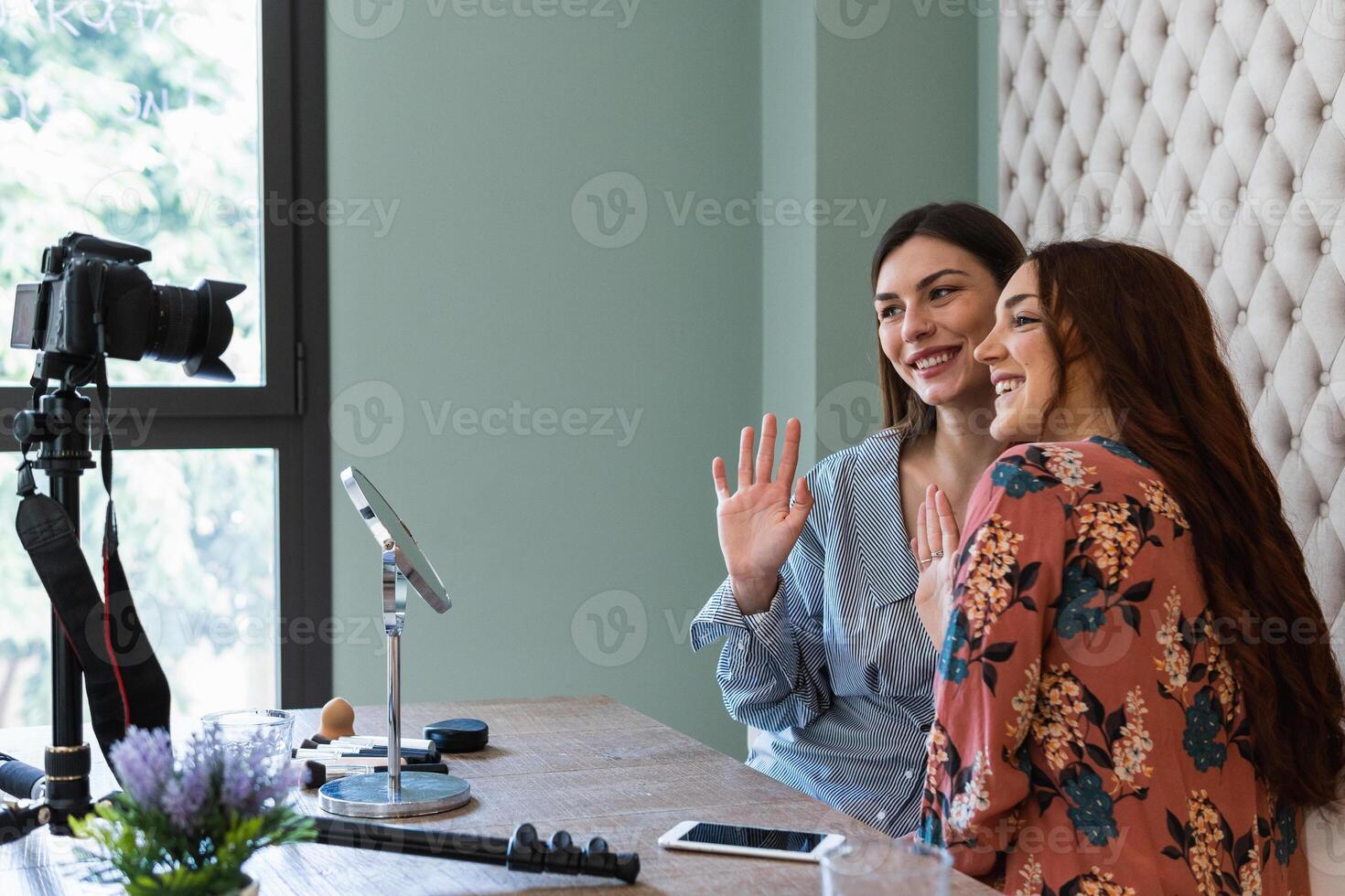 Cheerful young women recording while sitting at table photo