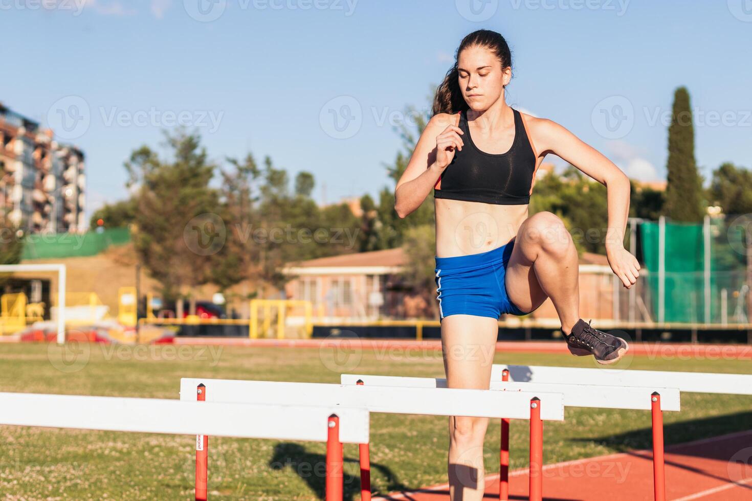 athlete training by jumping hurdles on an athletics track. photo