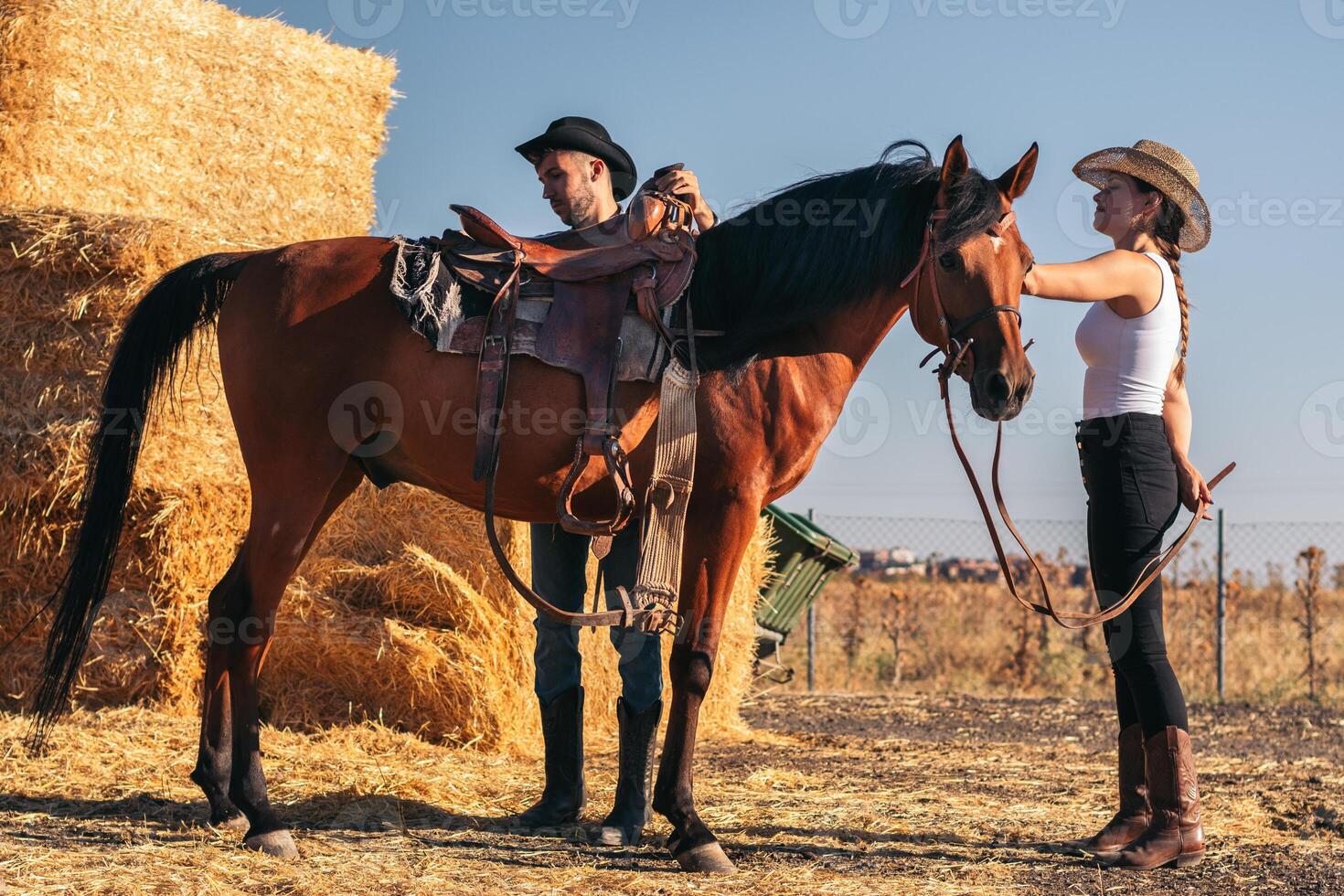 Friends saddling a horse in an equestrian center photo