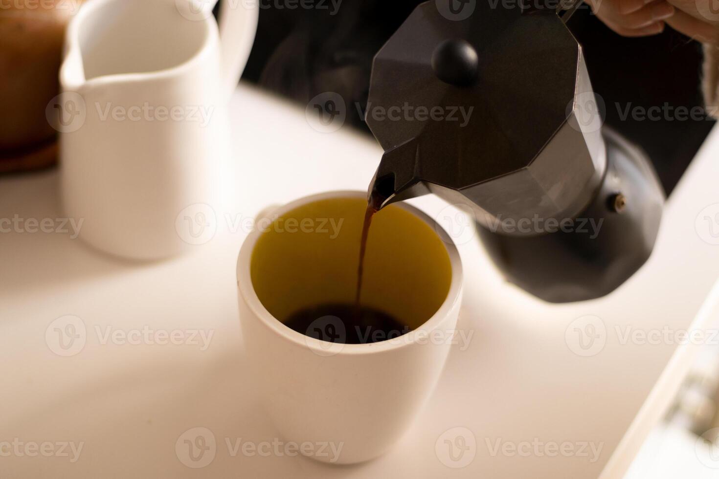 Pouring coffee on a cup in a kitchen. photo