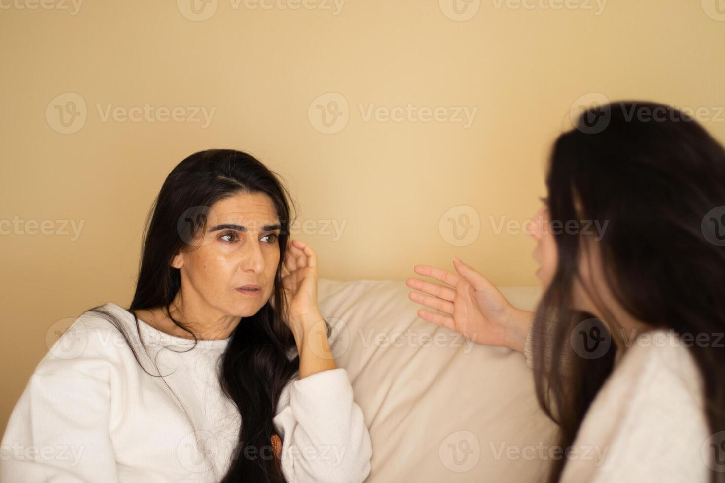 Mother and daughter discussing sitting on a sofa photo