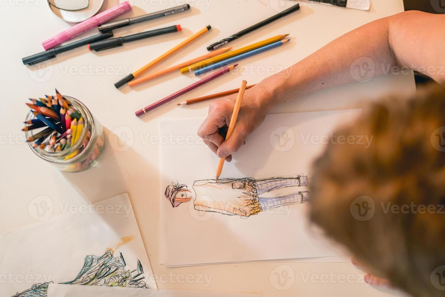 Top view of a fashion designer drawing a fashion sketch with colorful pencils photo