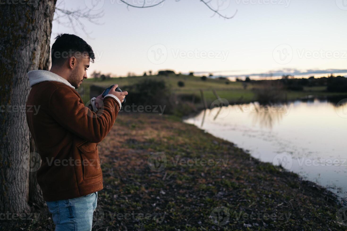 Photographer man taking photos of a lake at sunset