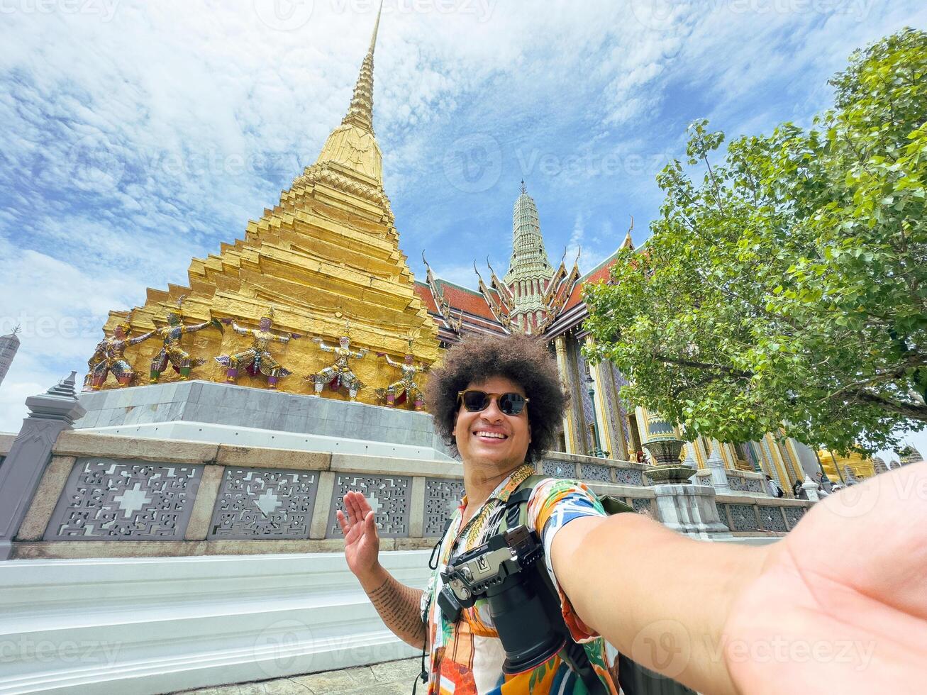 Tourist takes a selfie with a beaming smile in a historic golden temple in Asia. photo