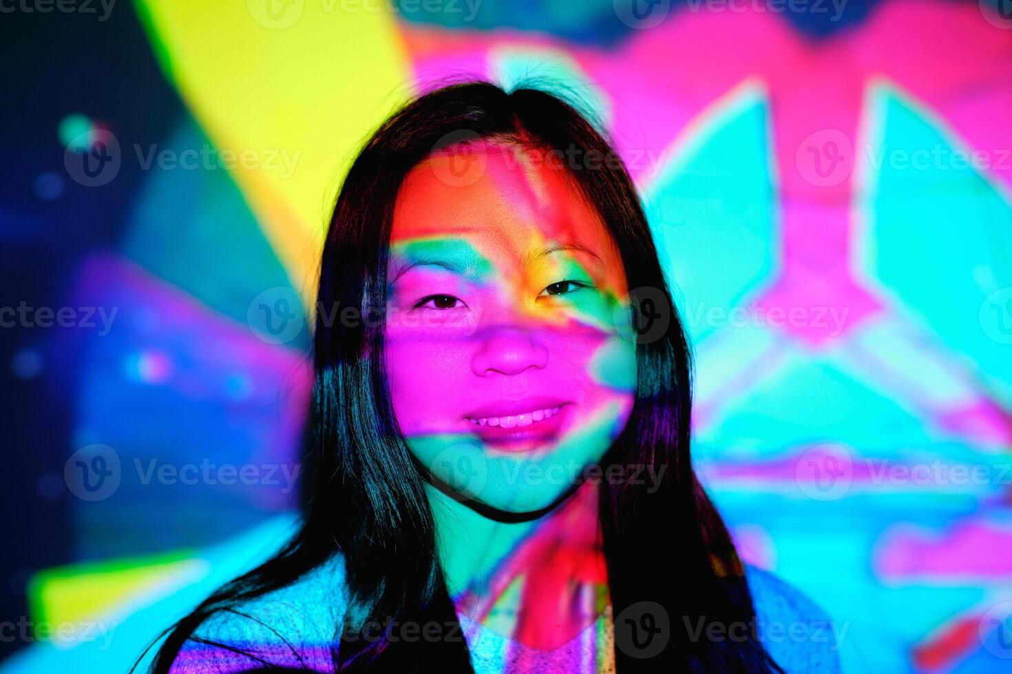 Smiling Asian woman under colorful lights photo