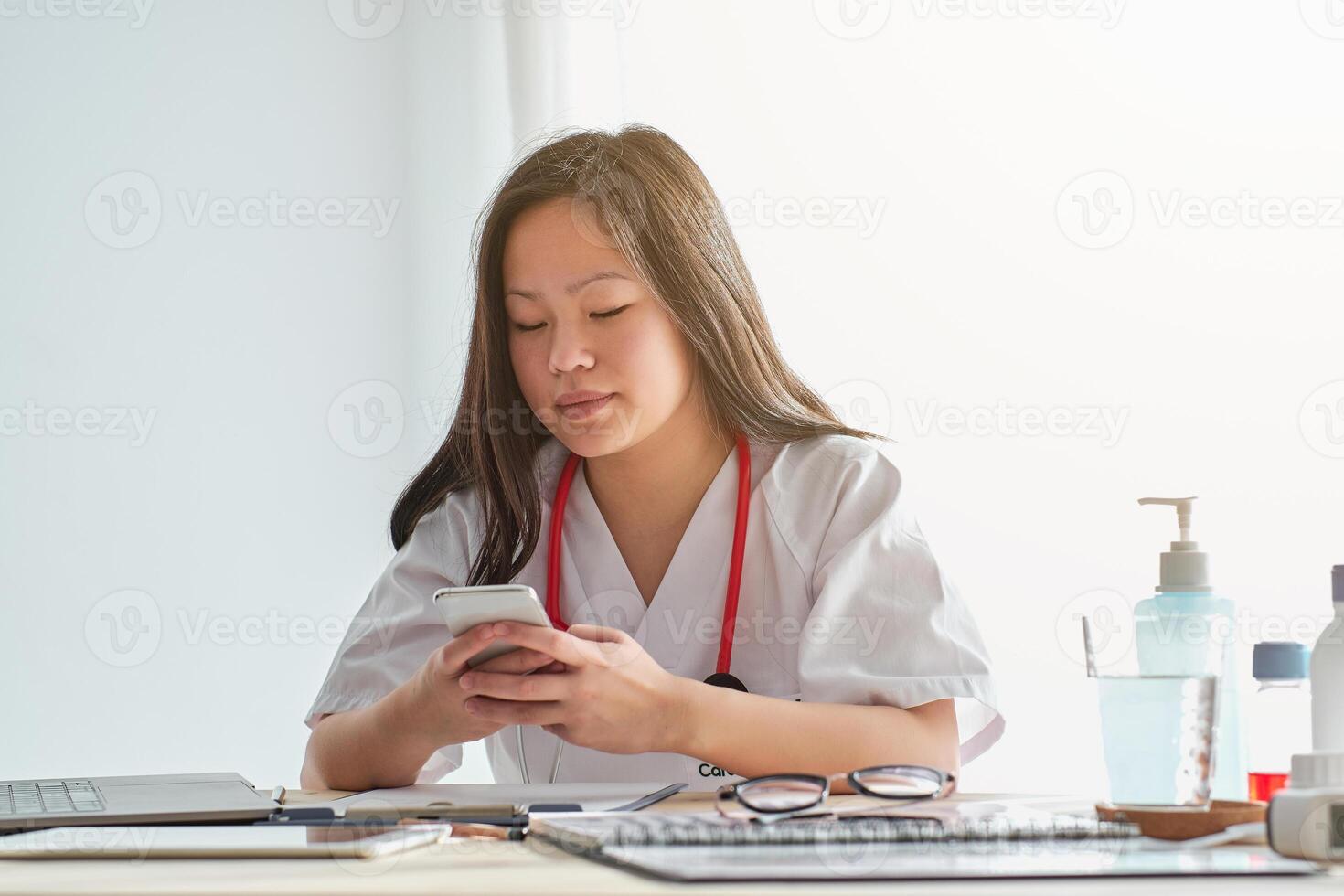 Focused Asian doctor browsing smartphone in hospital photo