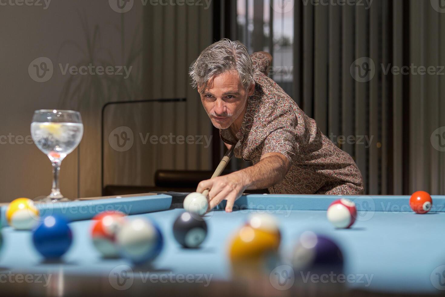 Handsome man leaning over the table while playing pool photo
