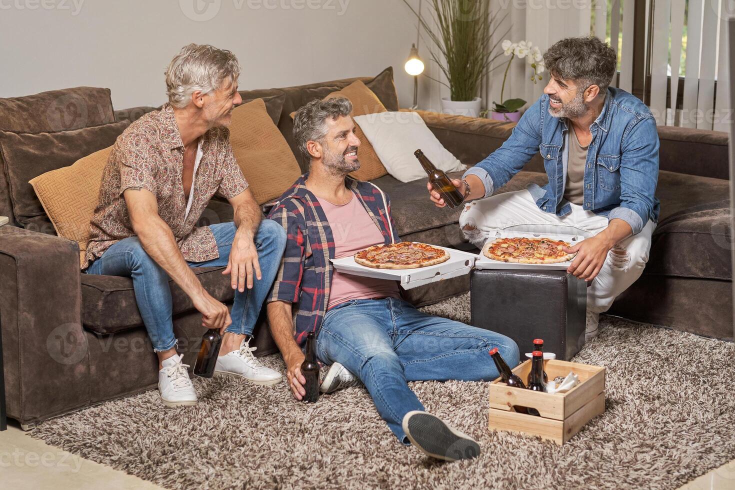 Happy friends having pizza and beer at home photo
