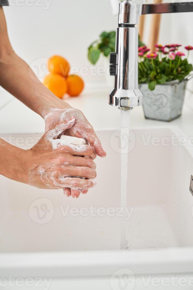 Person washing hands with soap and water in basin photo