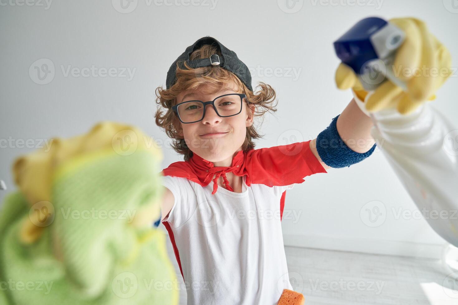 Content child in superhero costume wiping camera against white w photo
