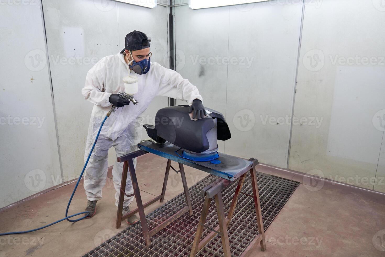 Male mechanic painting motorbike tank in garage photo