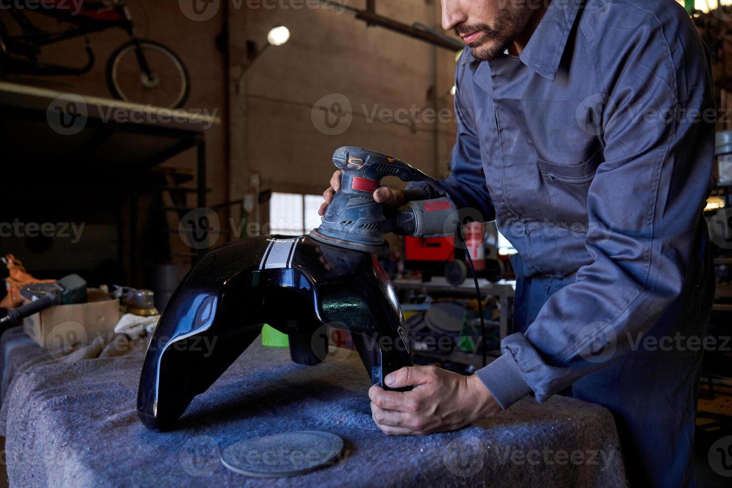 Crop mechanic repairing car in dark garage photo