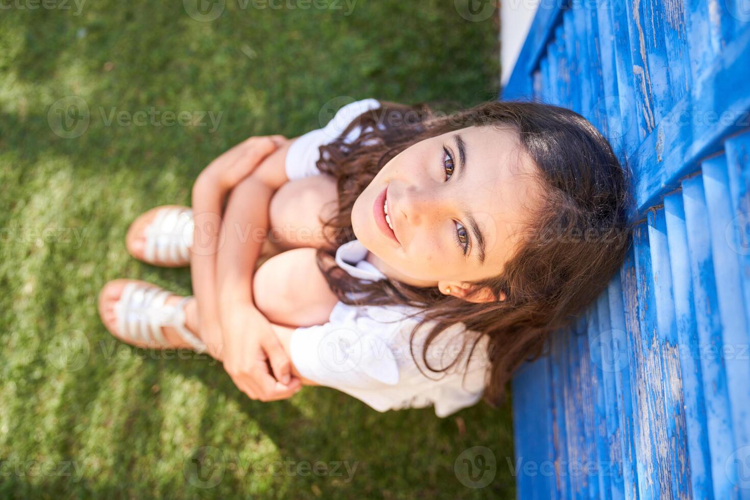 Preteen child hugging knees in garden photo