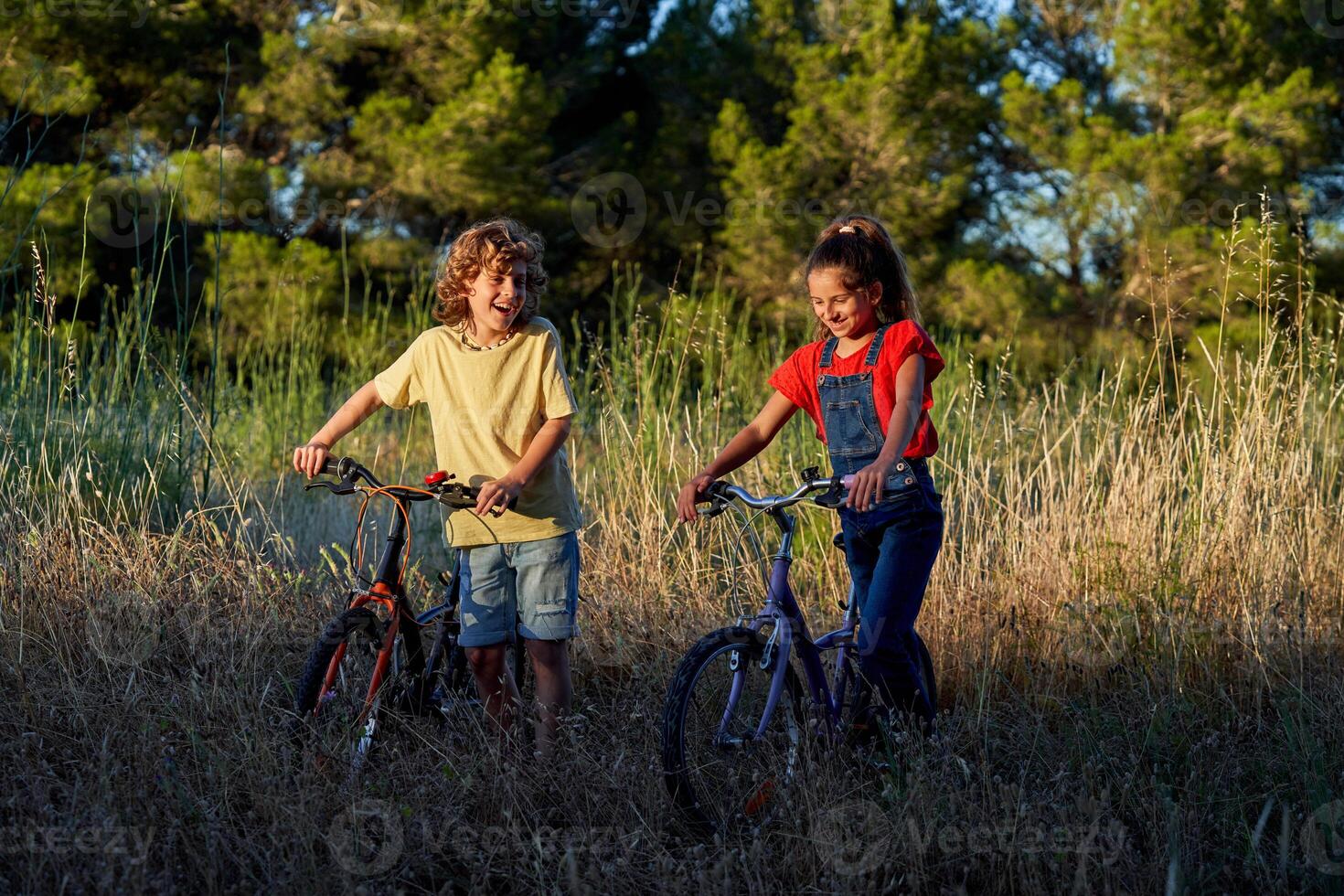 Happy children walking with bicycles on rural road photo