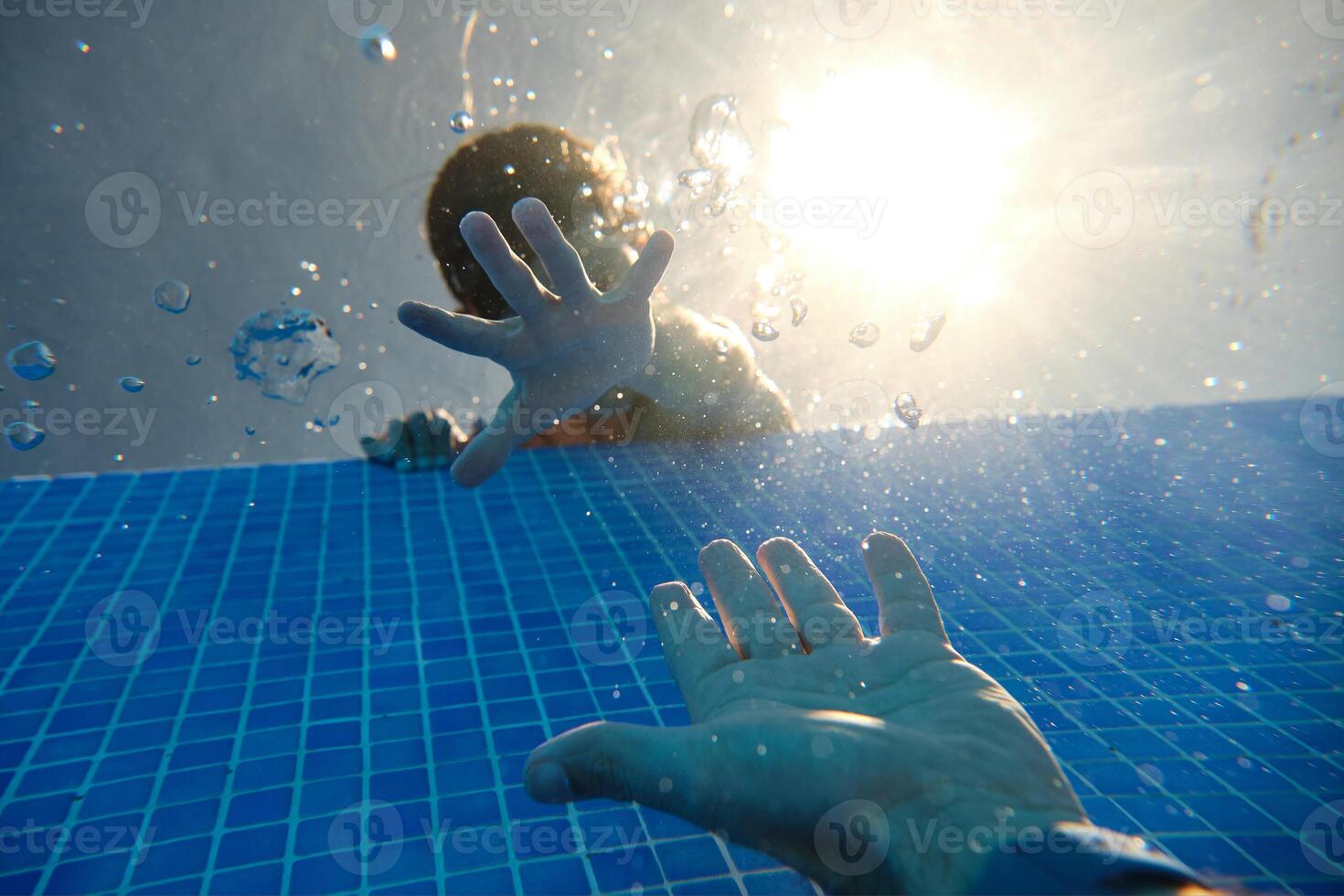 Unrecognizable boy and man reaching out hands in pool photo