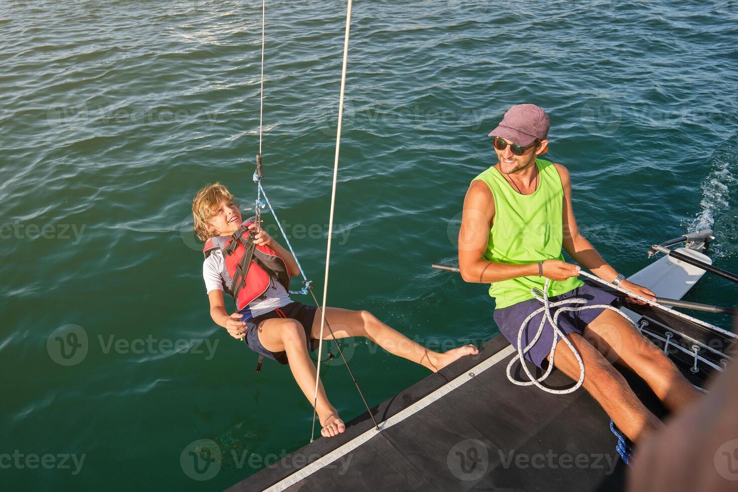 Smiling guy pulling rope with happy kid to make counterweight on photo