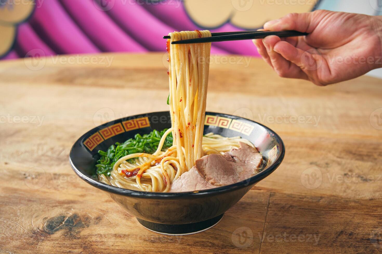 Crop person with noodles on chopsticks above delicious ramen photo