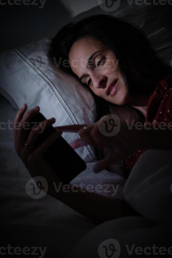Hispanic woman browsing smartphone at night time photo