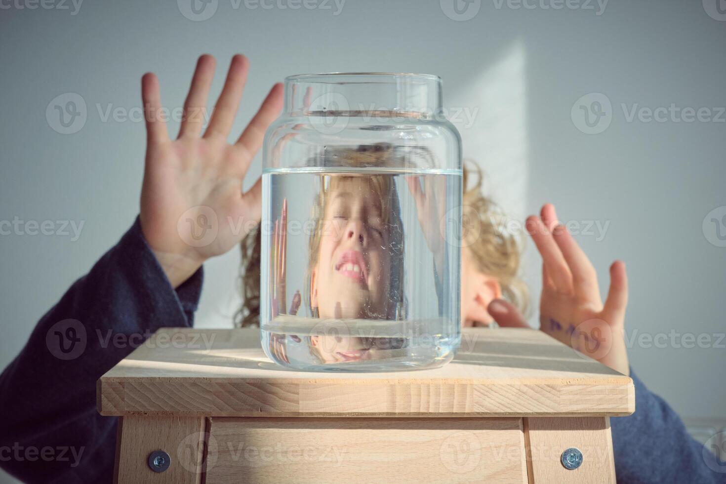 Terrified boy reflection in glass jar with water photo
